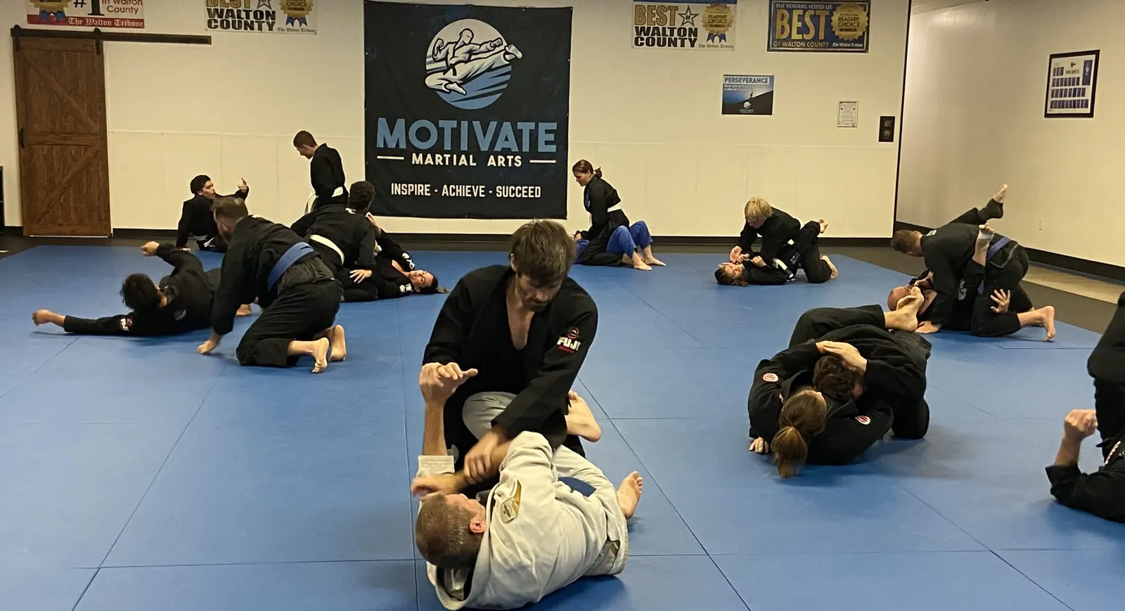 An Adult BJJ class training in gis on the blue mats