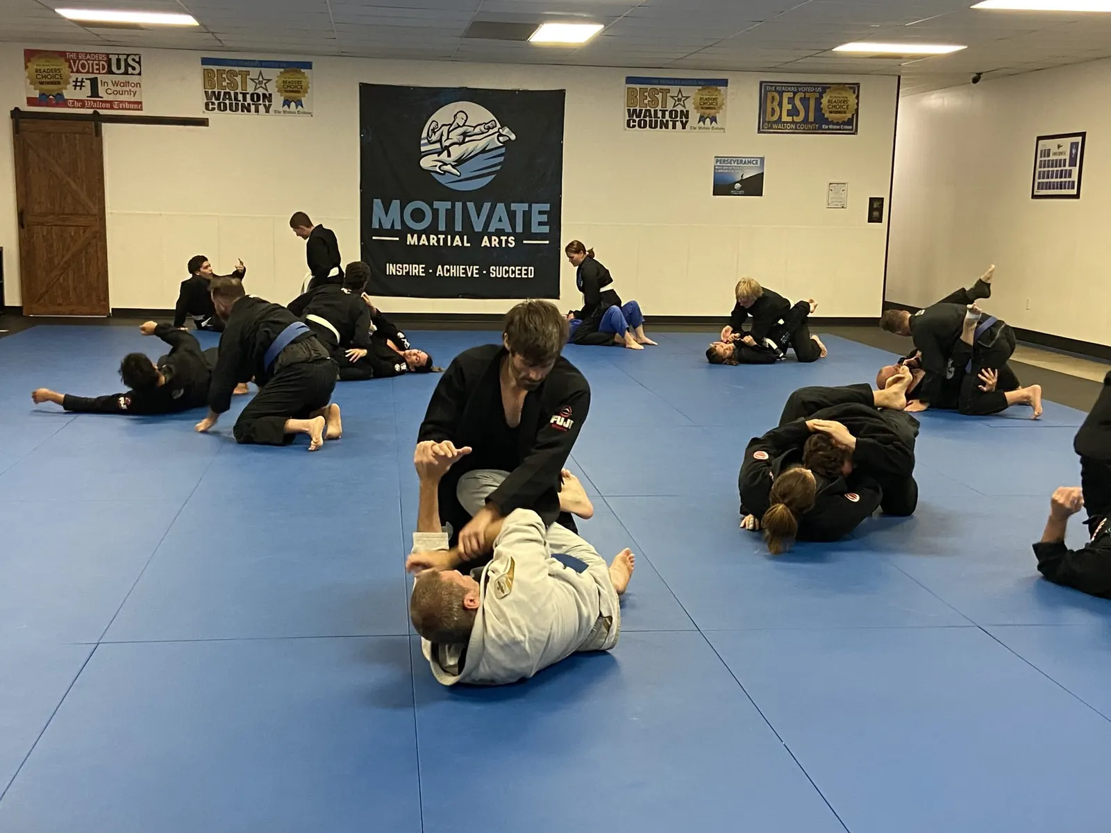An Adult BJJ class drilling in gis on the blue mats