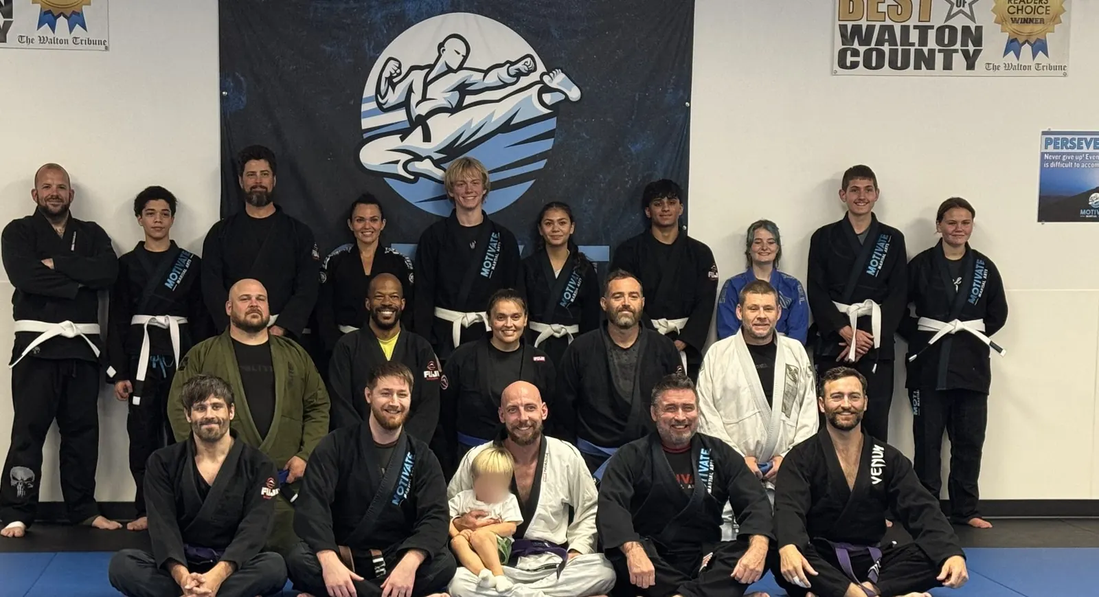 The Motivate Adult BJJ team in their gis on the blue mats