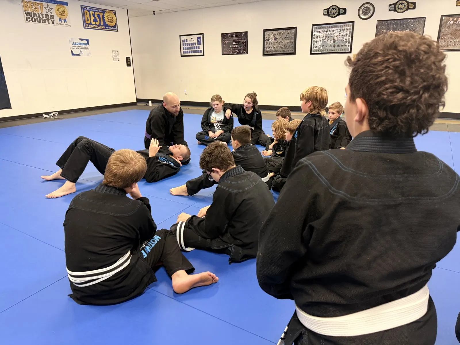 Juniors BJJ students watching a coach demonstrate a technique