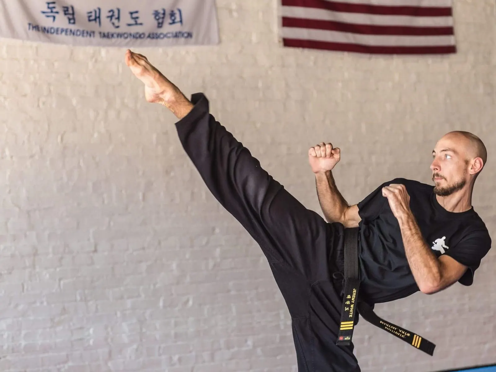 A Motivate TaeKwonDo black belt throwing a high side kick in the studio